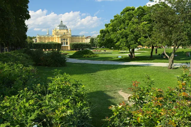 Parc verdoyant avec bâtiment jaune historique, rivière et arbres en Croatie