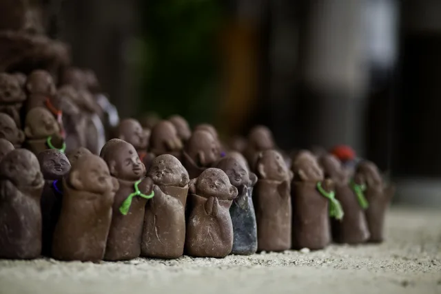 Petites statues de terre avec foulards verts alignées sur le sable