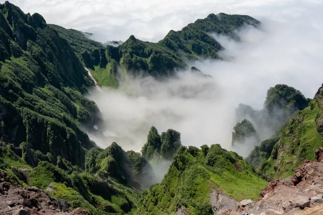 Montagnes verdoyantes shrouded in mist during Hokkaido trek with dramatic peaks