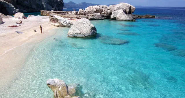 Plage méditerranéenne avec eau turquoise, rochers blancs et sable fin en Italie
