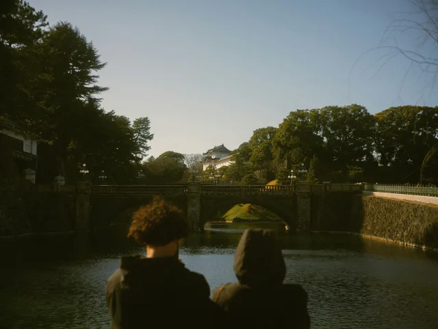 Couple admirant le coucher de soleil devant un temple japonais depuis un pont en pierre