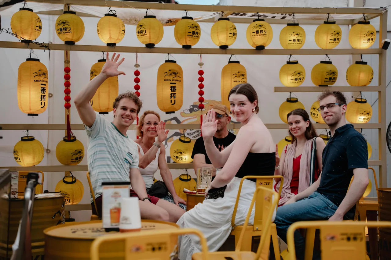 Groupe d'amis célébrant dans un izakaya japonais avec lanternes jaunes en arrière-plan