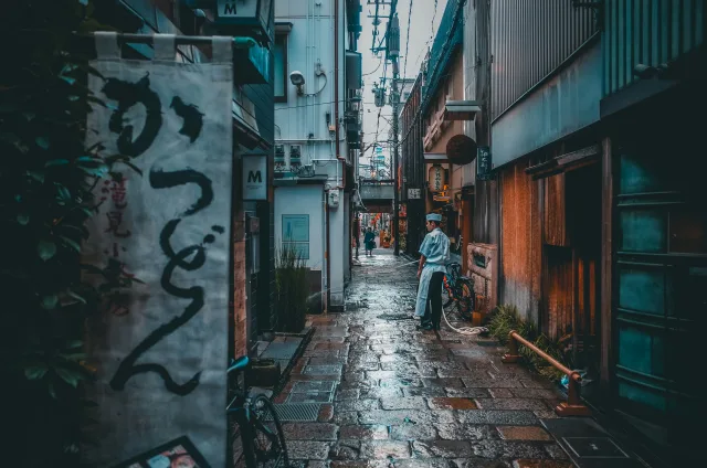 Ruelle étroite et humide du Japon avec graffitis, cycliste et bâtiments traditionnels