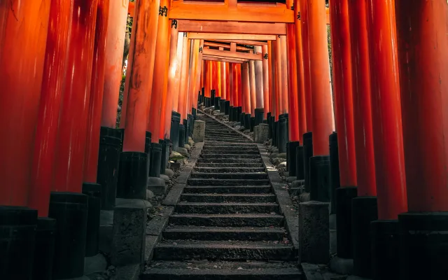 Allée de portes torii rouges traditionnelles au Japon avec escalier en pierre