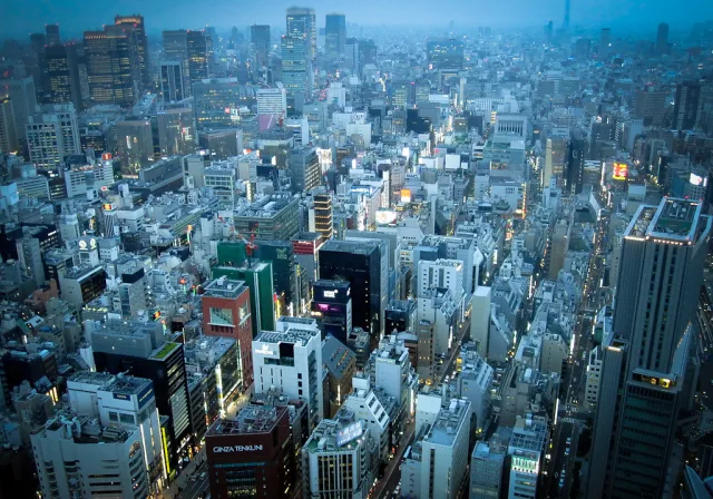 Vue aérienne d'une métropole japonaise densément construite au crépuscule avec immeubles illuminés
