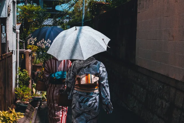 Deux femmes en kimono et parapluie blanc explorant une ruelle traditionnelle au Japon