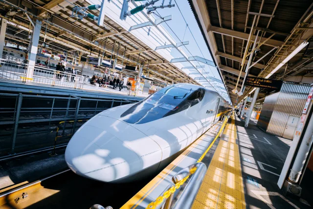 Train à grande vitesse Shinkansen blanc stationné en gare sous une verrière métallique moderne