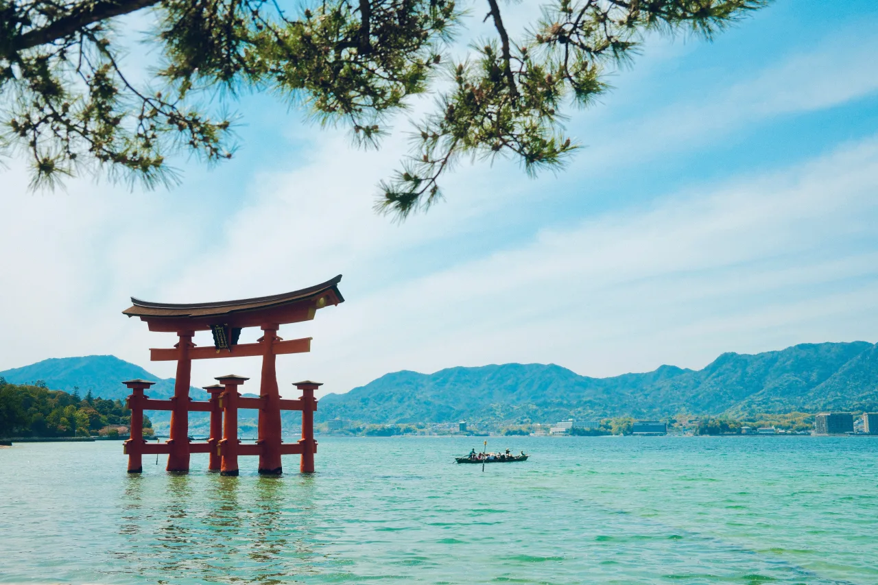 Grand torii rouge dans l'eau avec montagnes et bateau au Japon