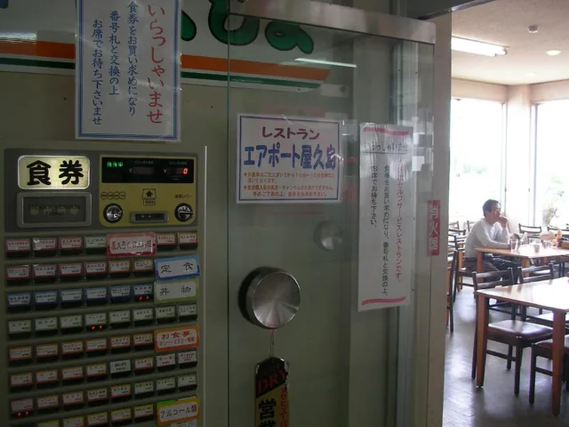 Distributeur de tickets de restaurant japonais avec panneaux en caractères kanji dans une salle à manger