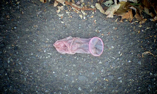 Filet de pêche rose abandonné sur une route pavée avec feuilles mortes